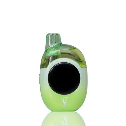 A green and white disposable vape device with a black circular screen, shown on a reflective white background.